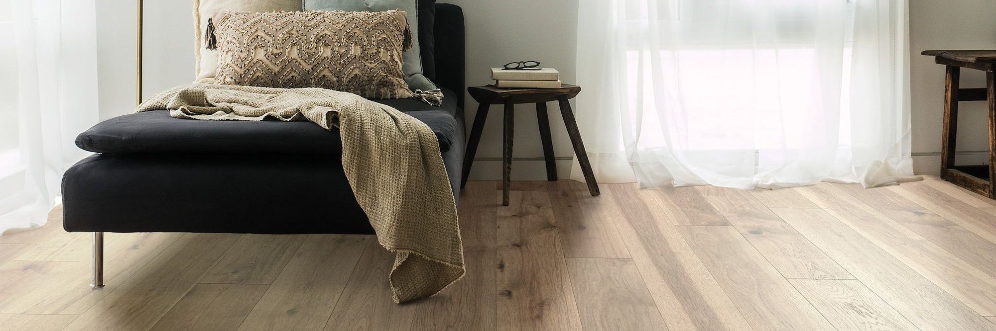 A bed having pillows on it and a chair with some eye glasses on it in the bedroom with hardwood floor from Sams Floor Covering in Winchester, KY